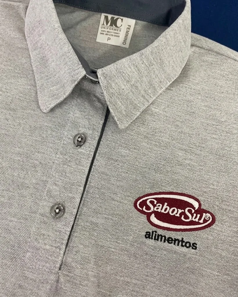 Detalhe da gola de camisa polo cinza com etiqueta MC Uniformes e logo bordada