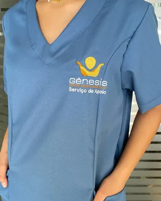 Scrub azul com decote em V e logo bordada, produzido pela MC Uniformes